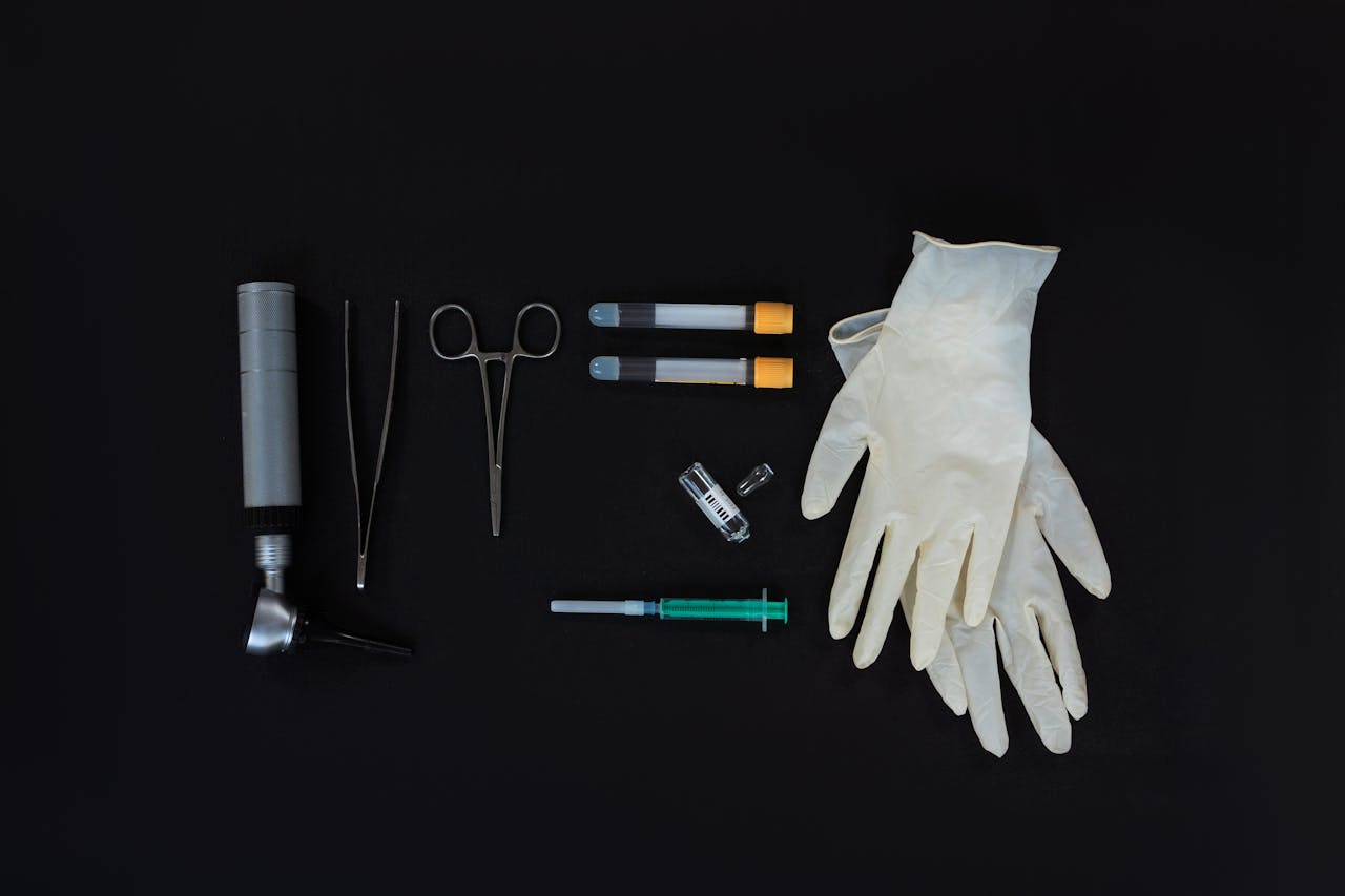 Flat lay of essential medical tools on a black background, including gloves and syringe.